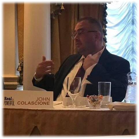 John Colascione speaking at a table during a professional event